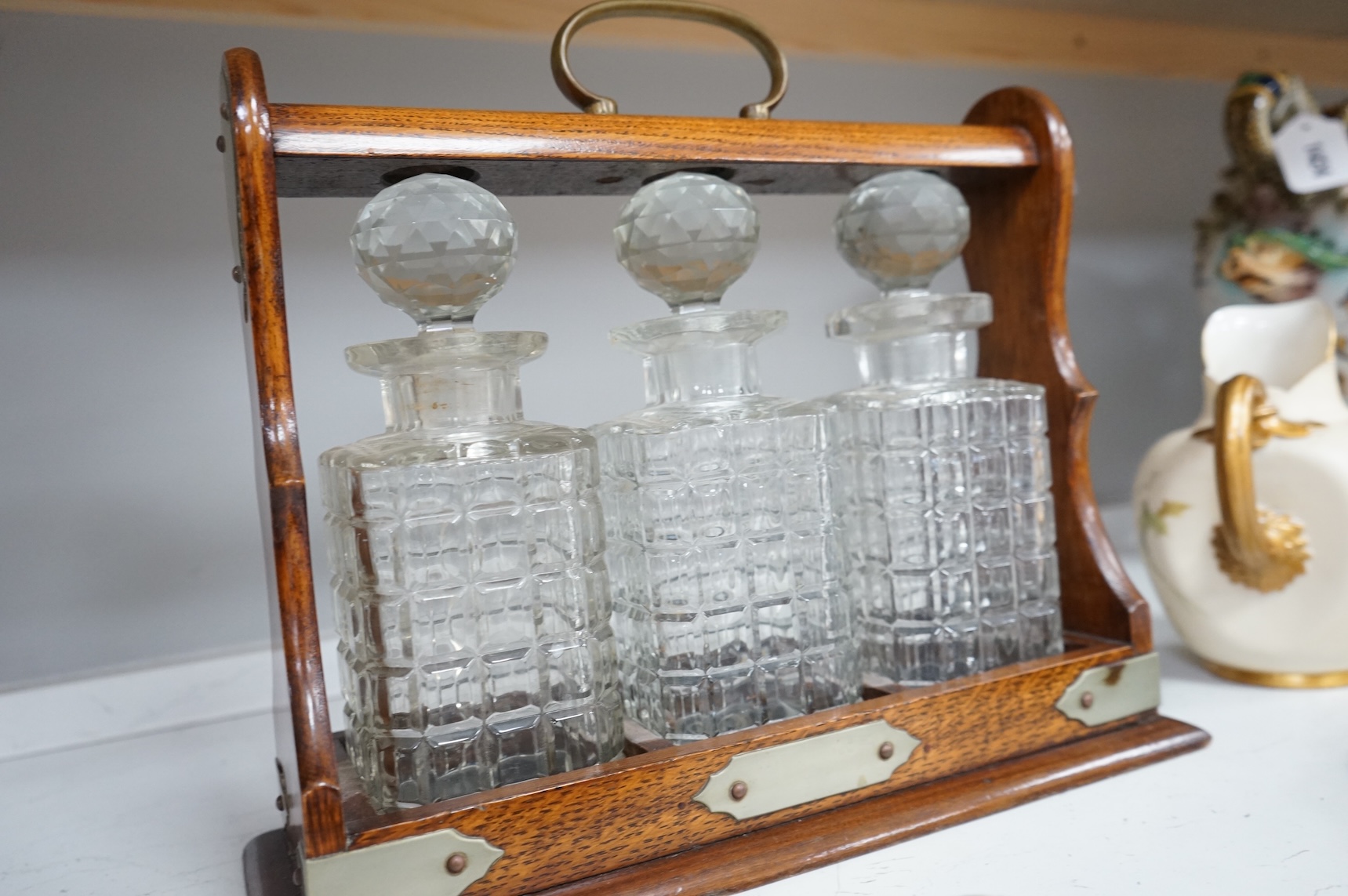 An oak three bottle tantalus, with key, together with three 18th/19th century faience plates and a Royal Worcester jug, tantalus 36cm wide